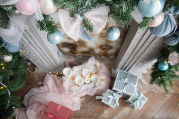 Fototapeta na wymiar Christmas, xmas, New Year interior with white fireplace, candles, pink and turquoise fur-tree decoration with balls and bowknots, ribbons, shallow doff, top view