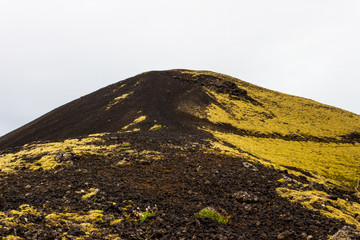 Lonely black  gravel volcanic mountain covered in green moss and grass. Volcano crater, Iceland