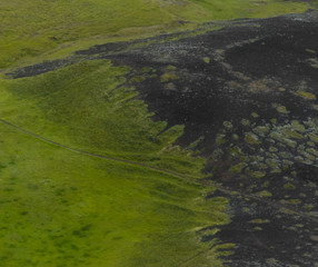 Volcanic landscape detail from, lava flow covering green fields, aerial from above