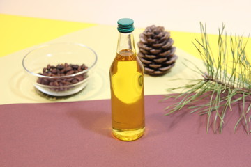 Bottle of golden cedar oil on colorful background with cone, nuts, branch