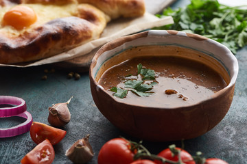 Soup kharcho with cilantro and adjarian khachapuri at background