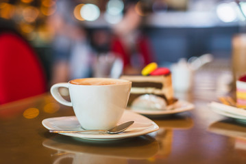 Closeup white cup of coffee on table in coffee shop cafe with shallow focus on a blurry light bokeh background