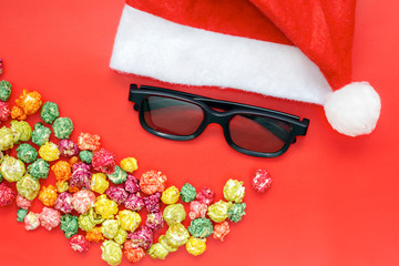 Christmas Hat, 3D glasses and pop corn on red background. Cinemas, movie times concept. Greeting card with Santa Claus