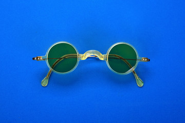 Yellow vintage sixties-like sunglasses isolated on blue paper background.