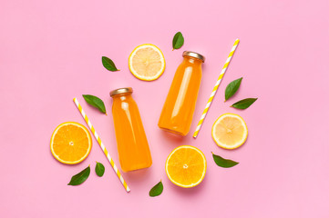 Flat lay composition with glass bottles of juice or fresh, slices of fresh lemon and orange, green...