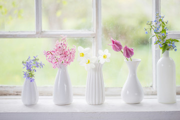 spring flowers in white vase on old windowsill