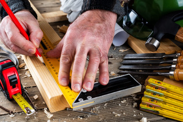Top view. Carpenter with pencil and the carpenter's square draw the line on a wooden board....
