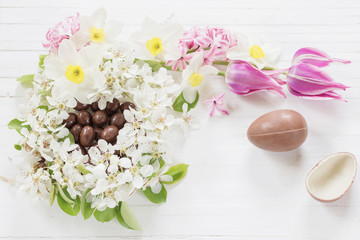 chocolate Easter eggs with spring flowers on wooden background