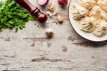 top view of delicious khinkali near vegetables and spices on wooden table