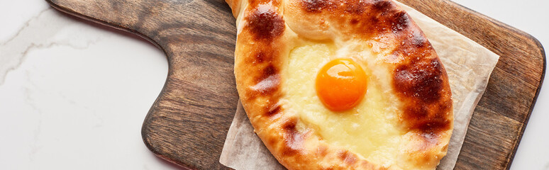 Top view of adjarian khachapuri on cutting board on marble texture, panoramic shot