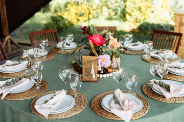 Round festive table with a green tablecloth decorated with bright peonies and greens