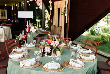 Round festive table with a green tablecloth decorated with bright peonies and greens