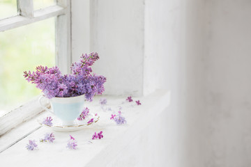 bouquet of lilacs in ceramic cup  on old white windowsill