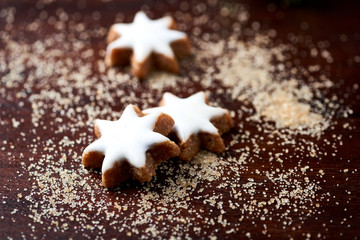 Christmas cookies (cinnamon stars) and brown sugar on dark background. Close up. 