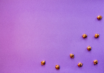 Shiny golden hearts on a purple background. Flat lay. Happy Valentine.