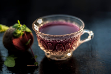 Best detoxify drink on a black glossy surface in a glass cup. Beetroot tea in a transparent glass...