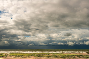 View of baby dunes with the surf behind it under a heavy dark storm sky