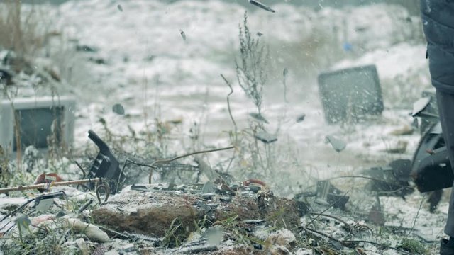 A person smashes old TV with a hammer at a landfill. Man crashes old TV set.