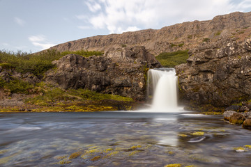 Waterfall in the mountains, river at tho foothill, in the valley