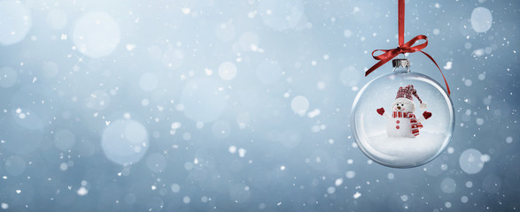 Happy snowman in the christmas bauble over the winter, snowy background with copy space