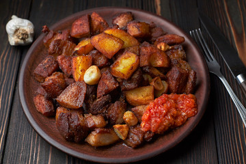 Homemade potato with meat, garlic, adjika, on wooden background