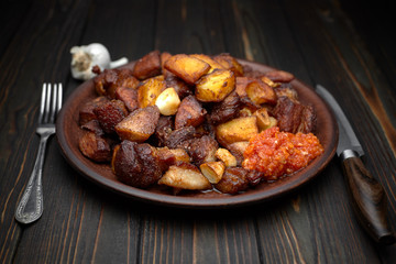 Homemade potato with meat, garlic, adjika, on wooden background