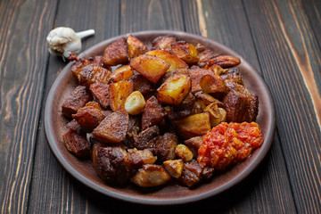 Homemade potato with meat, garlic, adjika, on wooden background
