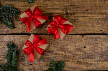Three christmas gift boxes with red bow on aged textured wooden background, with place for design or text.