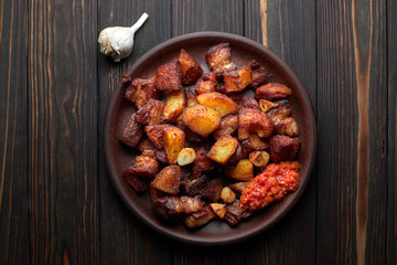 Homemade potato with meat, garlic, adjika, on wooden background
