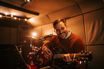 Portrait of a cheerful singing man with a guitar in the studio.