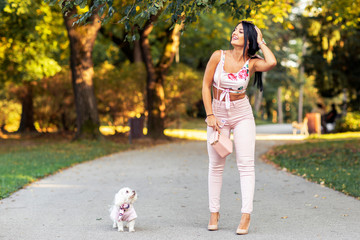 Fototapeta premium Fashion girl in park in pink with her small dog