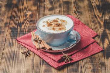 Eggnog. Traditional christmas cocktail in a mug with cinnamon sticks and anise on red napkin and wooden table.