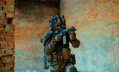 Man in uniform with machine gun and night-vision device, move in broken building. Airsoft soldier Aims at the sight in building. Horizontal photo