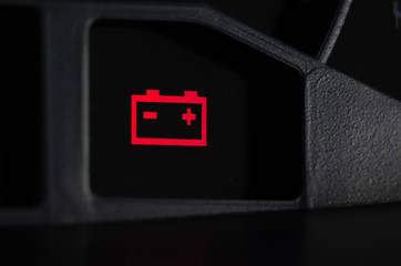 Close up shot of a car's dashboard with the battery icon lit.