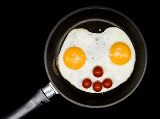 Scrambled eggs on a frying pan on a dark background.