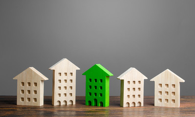 Green figure of a residential building stands out among the rest of the houses. eco-friendly and...