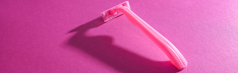 disposable feminine razor on pink background with copy space, panoramic shot