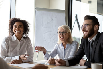 Smiling diverse colleagues laugh brainstorming at office briefing