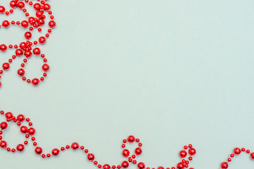 Red Christmas beads on light blue background. Christmas frame. The view from the top. Copy space