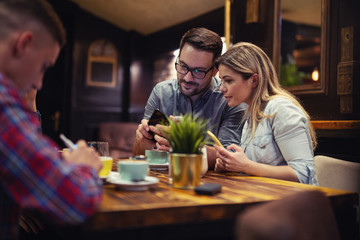 Attractive male showing something to his girlfriend while having a little coffee break.