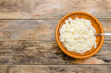 Cottage cheese in a brown bowl on a wooden background. Healthy Breakfast, top view, copy space