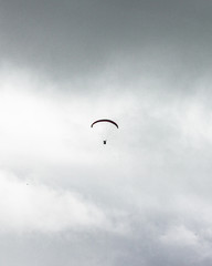 Paraglider in the sky, extreme adrenaline sport, Parachutist flying between clouds high above ground