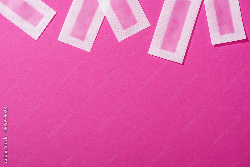 Wall mural top view of wax depilation stripes on pink background