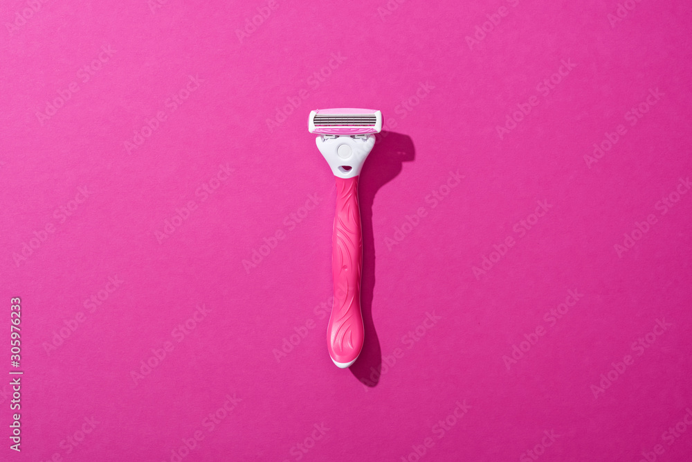 Wall mural top view of female shaver on pink background