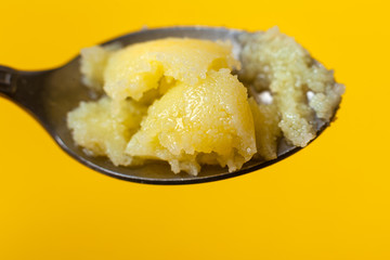 Homemade melted butter on a spoon. Ghee. Ayurveda. On a Colored yellow background