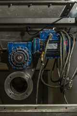 Close up image of blue mechanical pump or drive type industrial metal piece of heavy duty equipment. with metal hoses and built with clean and dirty rusty nuts and bearings 