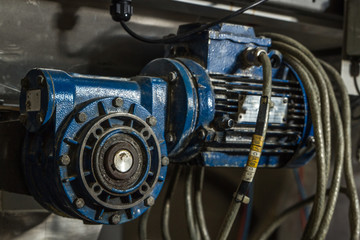 Close up image of blue mechanical pump or drive type industrial metal piece of heavy duty equipment. with metal hoses and built with clean and dirty rusty nuts and bearings 