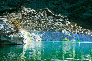 Reflection of sunlight from the surface of the lake on the ceiling of the cave in marble canyon in Ruskeala