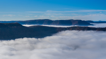 Fototapeta na wymiar Germany, Amazing aerial view above fog clouds in valley of swabian jura nature landscape on sunny day with blue sky near stuttgart