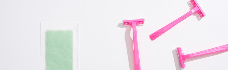 top view of female pink razors and depilation stripe on white background, panoramic shot